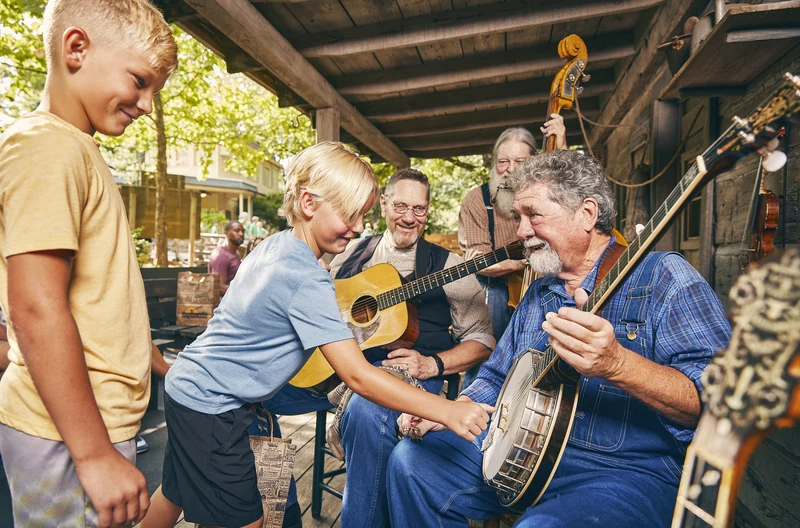 Children gather around the Homestead Pickers as musicians play banjo and guitar.